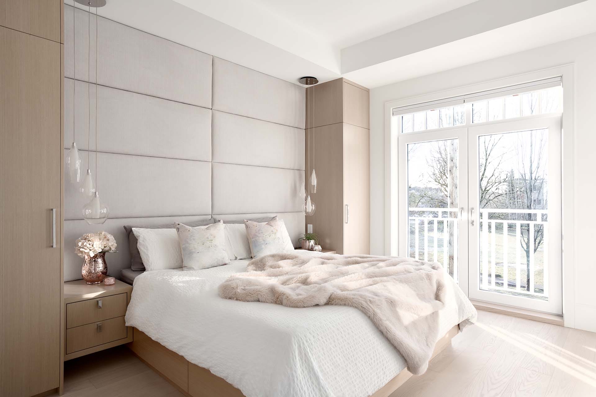 modern-home-interior-5 (15) A modern bedroom crafted by talented home designers features a large bed, light wood furniture, elegant pendant lights, and a window that opens to stunning outdoor views.