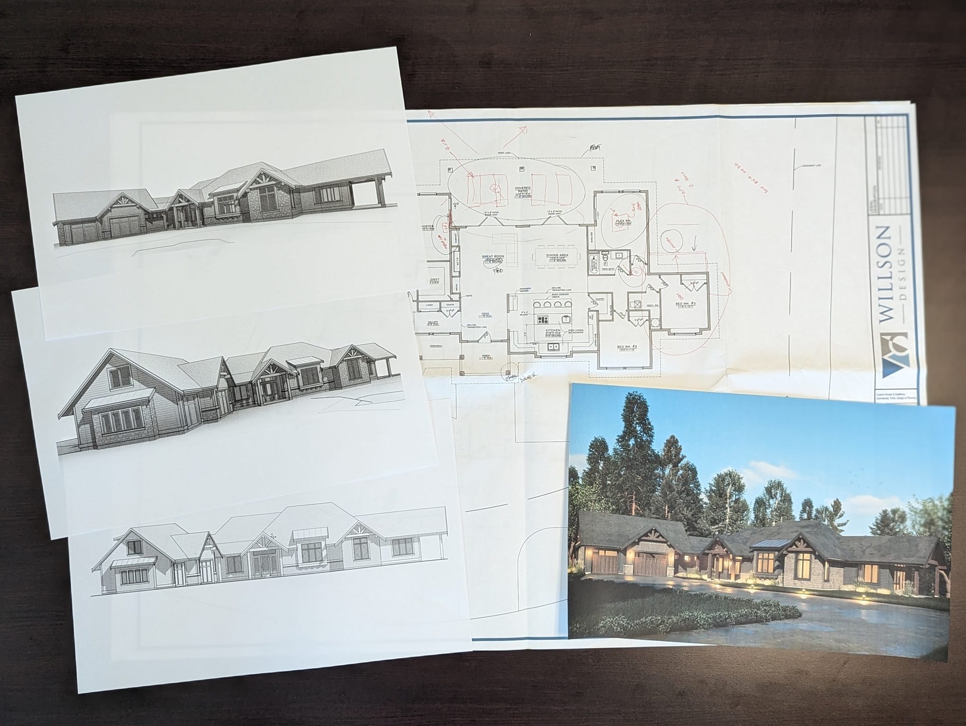 2-layout-exterior-design-process Architectural plans and sketches of a custom home design, with a color rendering on a table.